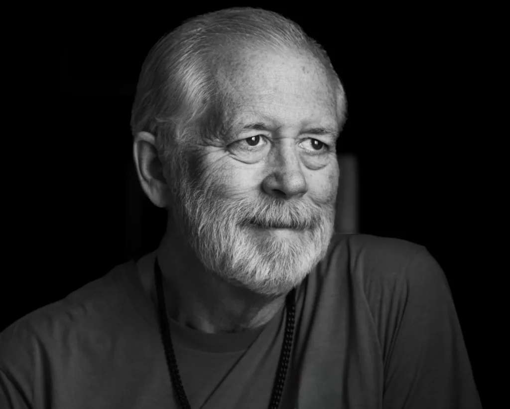 Black and white portrait of Larry smiling softly and looking off-camera against a dark background.