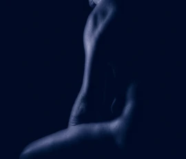 Blue Figure Study Blue-toned fine art image of Larry seated in profile with head lowered, defined by soft directional light against a dark background.