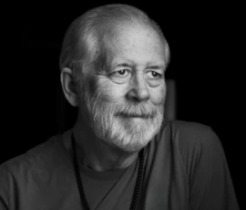 Quiet Smile Black and white portrait of Larry smiling softly and looking off-camera against a dark background.