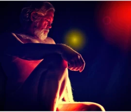 Seated Figure in Color and Shadow Color fine art image of Larry seated in dramatic red, blue, and yellow gel lighting, looking downward in a contemplative pose.